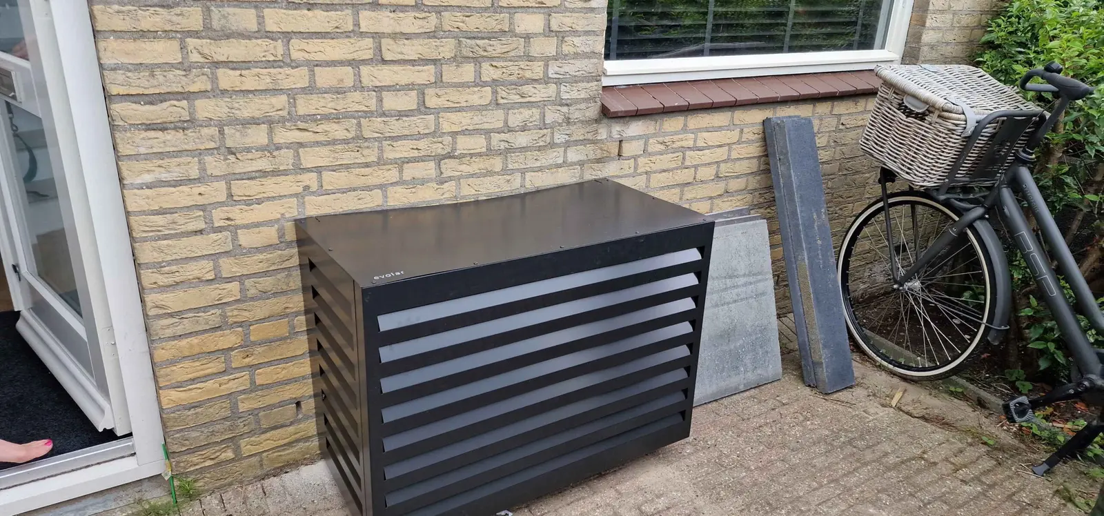 Warmtepomp-buitenunit met omkasting in een tuin