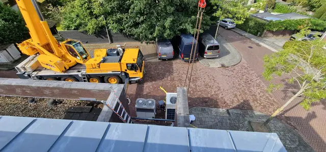 Hijskraan plaatst installaties op een dak