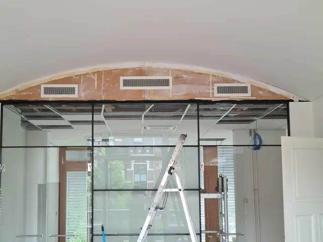 Ventilatieroosters boven een glazen pui