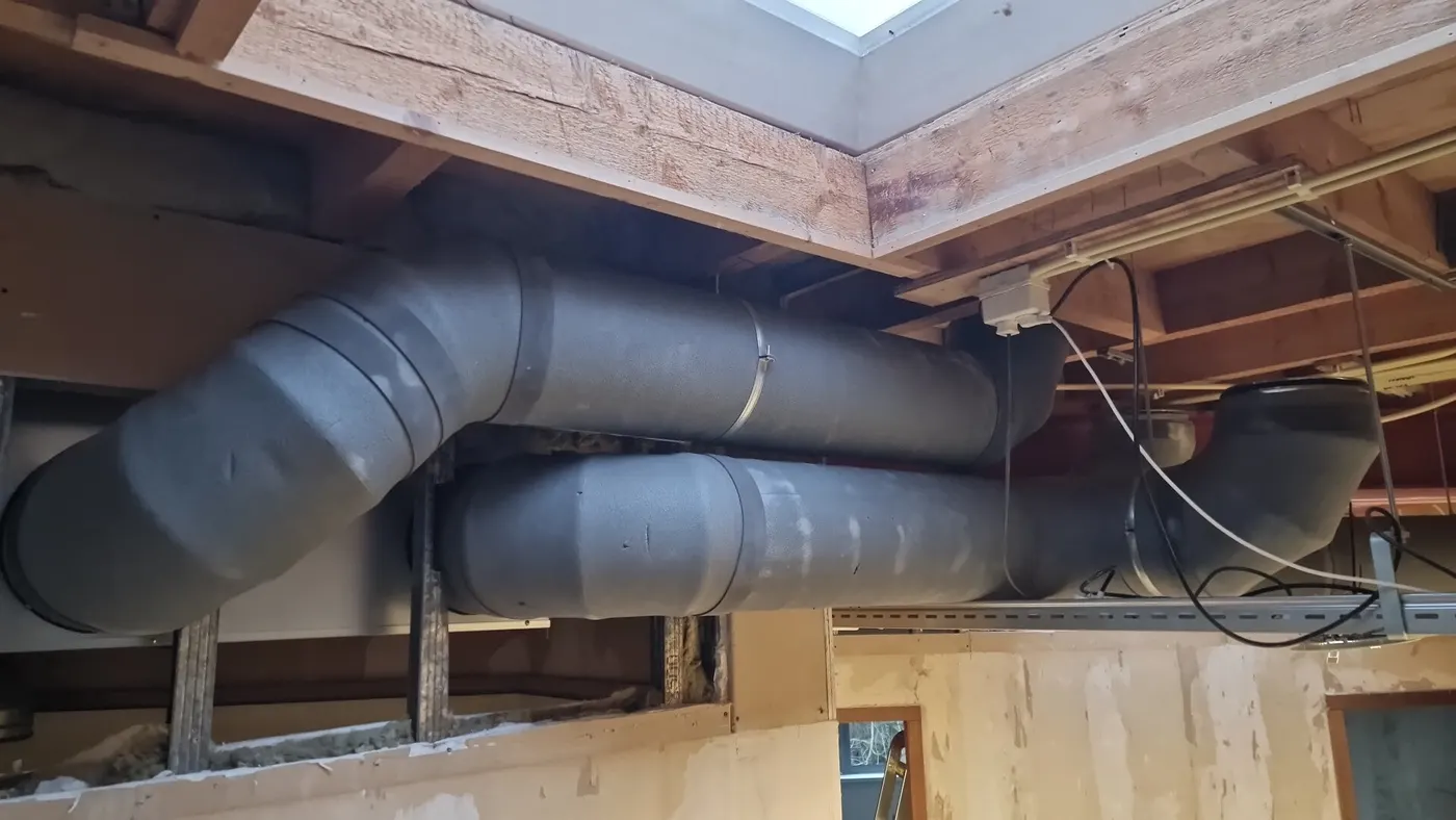 Geïsoleerde ventilatiekanalen onder een houten plafond