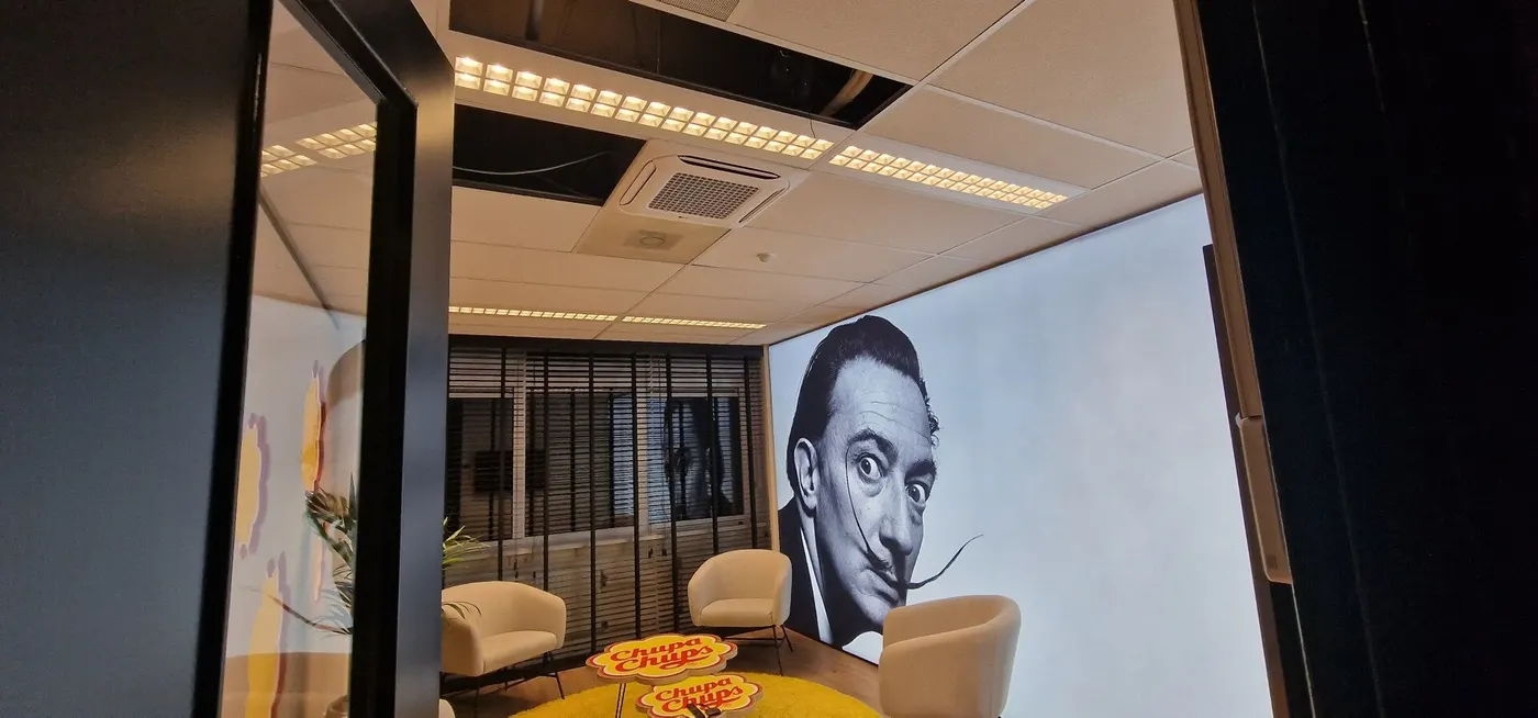 Loungeruimte met plafondcassette en een portret op de wand