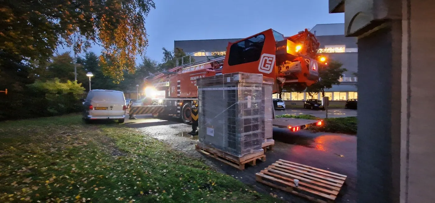 Buitenunits worden in de schemering met een kraan geplaatst